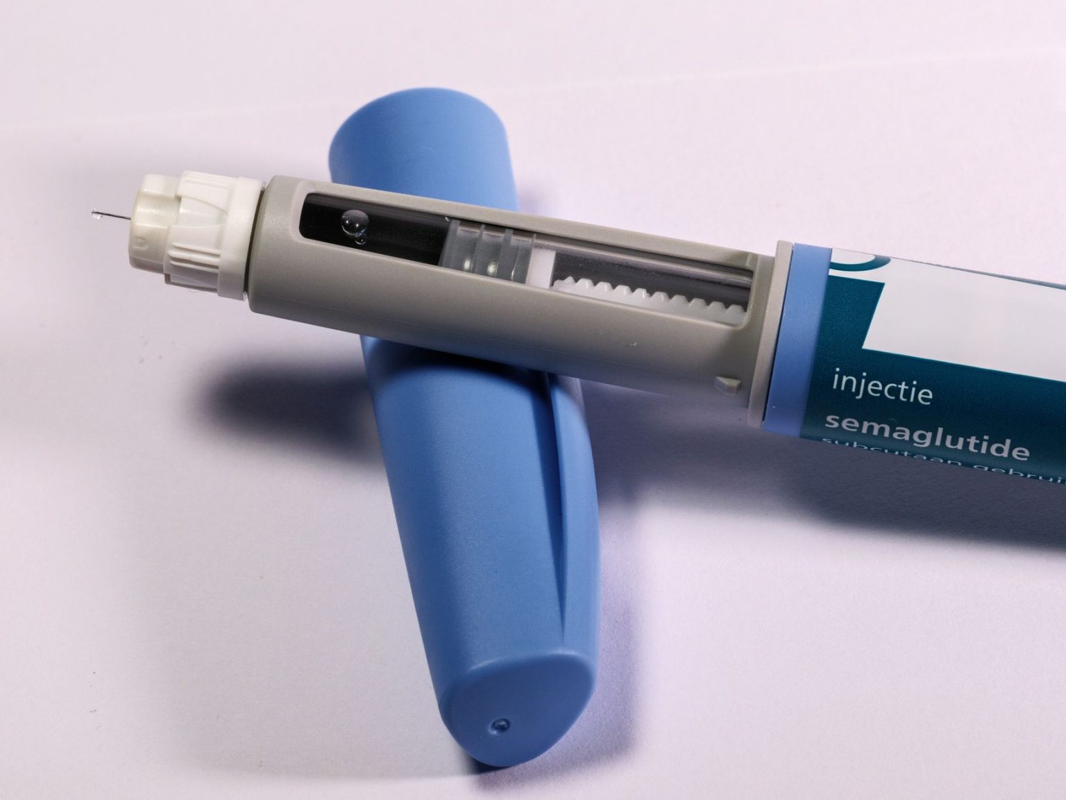 Caneta de aplicação de medicamento sobre fundo neutro.