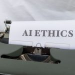 Máquina de escrever antiga com as palavras “AI ETHICS” datilografadas em uma folha de papel.