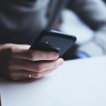 Mulher segura um smartphone com a mão, em close.