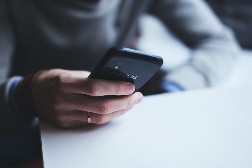 Mulher segura um smartphone com a mão, em close.